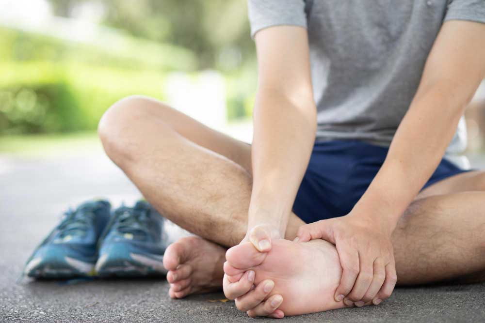 Man sitting on pavement holding his sore foot after a run, highlighting foot pain and injury treatment options from a trusted Foot Doctor Rockledge for expert foot and ankle care.