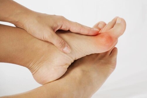 Close-up of person holding the ball of their foot with red inflammation highlight indicating forefoot pain, seeking professional podiatry services from merritt island foot and ankle.